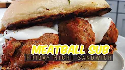 Two meatballs with a slice of mozzarella cheese inside a toasted submarine bun